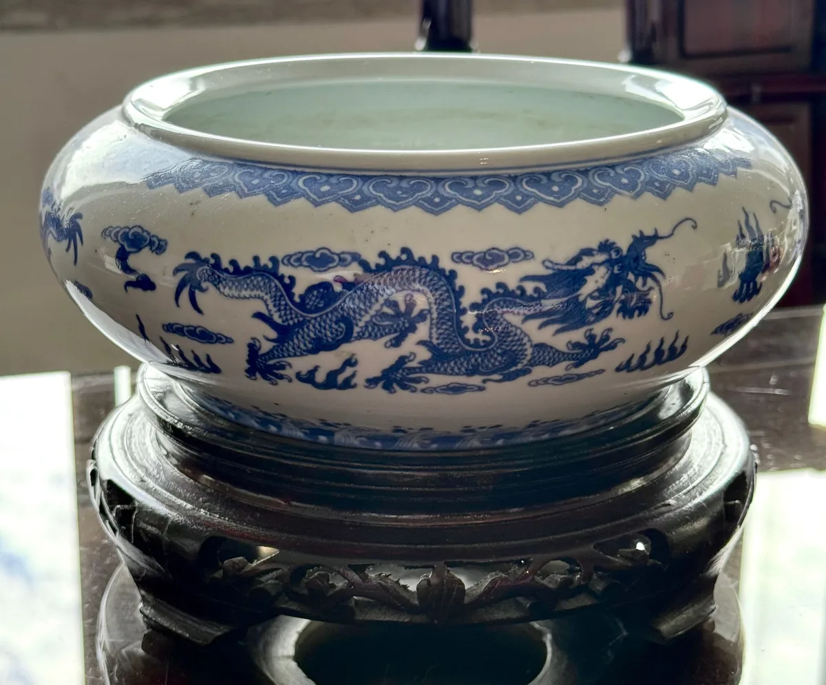 Taça-incensário chinesa em porcelana azul e branca com dragões, sobre base em madeira entalhada